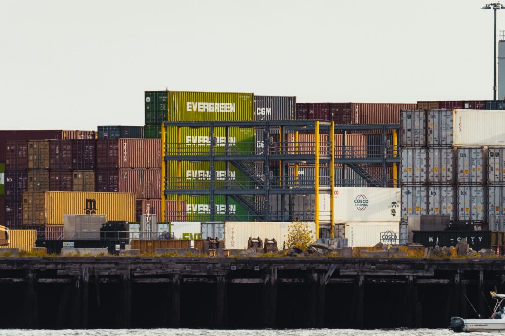 Stacked shipping containers at a port, representing international supply